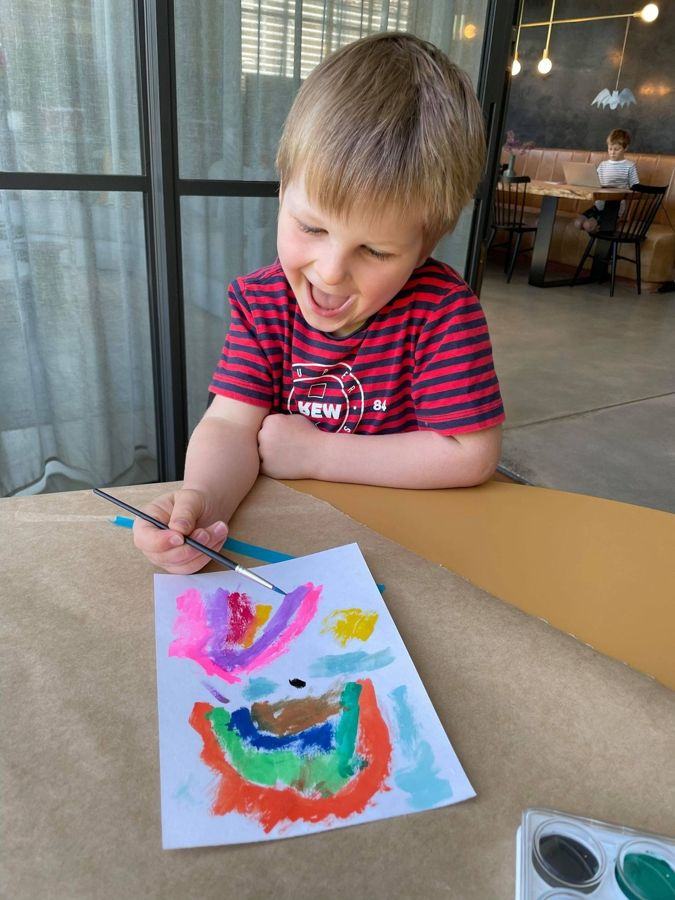 A boy happily painting at a holiday workshop